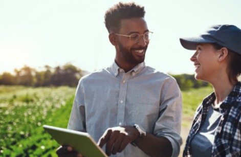 Two individuals discussing ideas near farmland