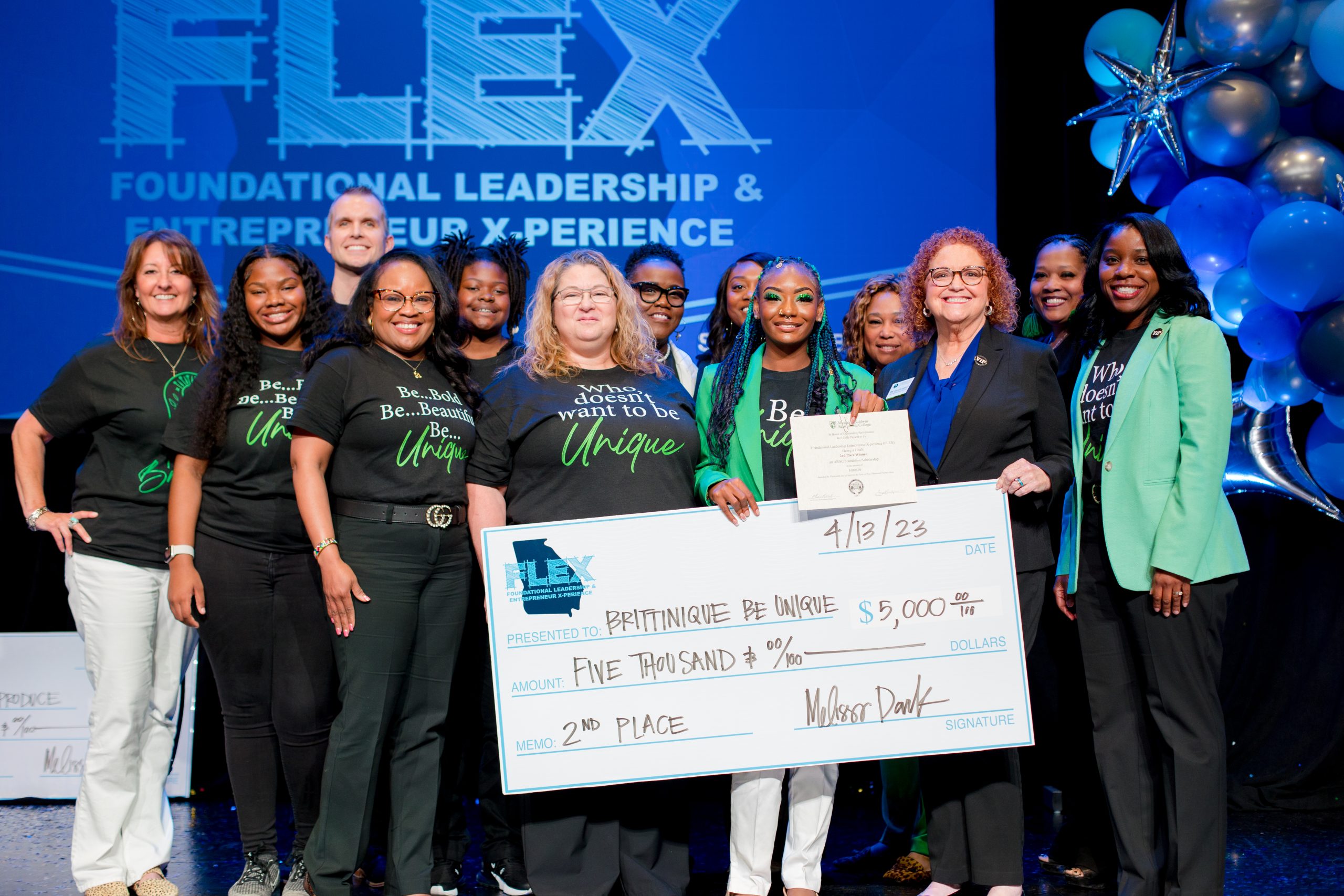 a group of individuals pose for a photograph holding a check for 5,000 dollars.