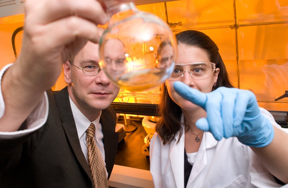 Two researchers investigating their development of a light source.