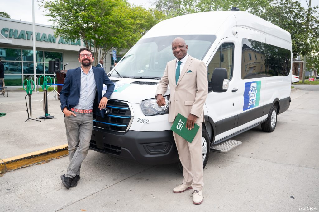 Two Chatham Area Transit Authority teammates stand with the transit system's new Smart Electric Vehicle.